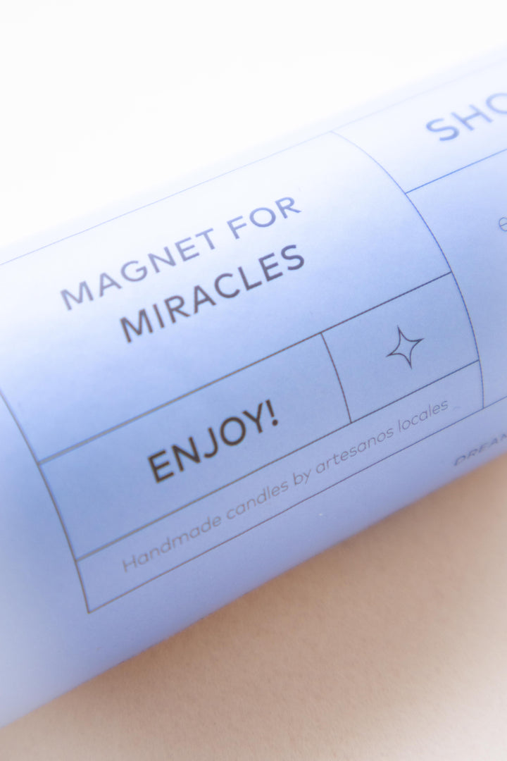 primer plano de etiqueta del ritual de luz 'Magnet for Miracles' para el Día de las Velitas en Colombia, con el mensaje 'hecho a mano por artesanos locales' y 'Enjoy!'